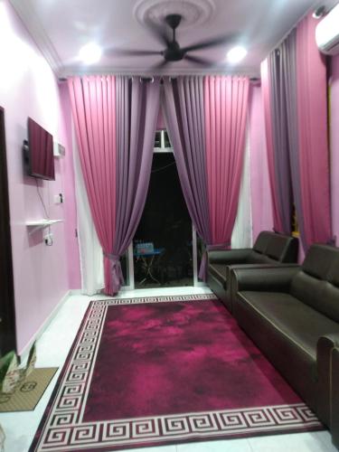 a living room with pink curtains and a couch at Homestay kak bee d' bendang in Jitra