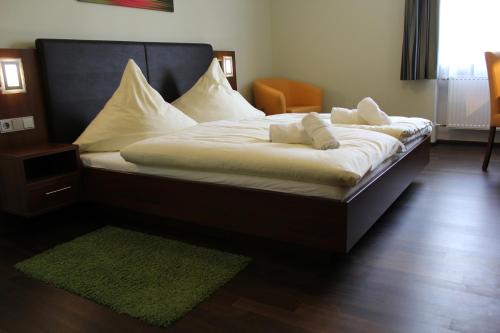 a bed with white sheets and pillows in a room at Hotel Brantl in Roding