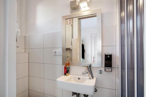 une salle de bain blanche avec un lavabo et un miroir dans l'établissement City Spa Haus Lörrach, à Lörrach