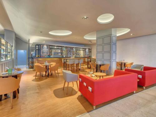 Un restaurante con muebles rojos, mesas y sillas. en ibis Bengaluru Outer Ring Road, en Bangalore