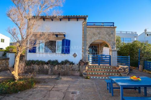 ein Haus mit einem blauen Tisch davor in der Unterkunft Punta Llarga in Colònia de Sant Pere