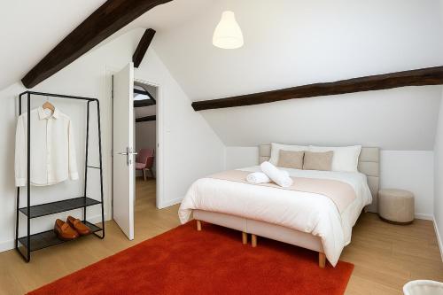 ein Schlafzimmer mit einem weißen Bett und einem roten Teppich in der Unterkunft Le Nest in La Celle-sous-Gouzon