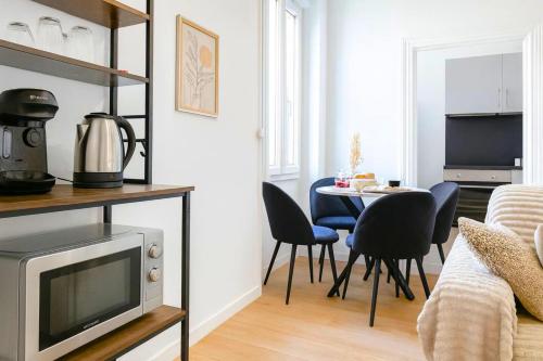 ein Wohnzimmer mit Fernseher und Tisch mit Stühlen in der Unterkunft Le Nest in La Celle-sous-Gouzon