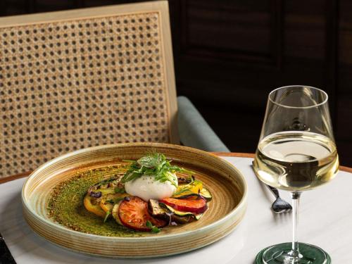 un plato de comida junto a una copa de vino en Sofitel Dubai Downtown, en Dubái