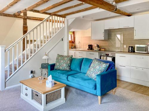a living room with a blue couch and a kitchen at The Yeomans Cottage, Eastbridge Hospital in Canterbury