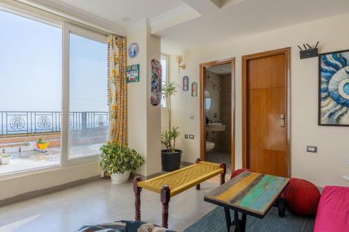 a living room with a table and a large window at The Sky Penthouse - Mussoorie Rd Da Alohas Retreat in Dehradun