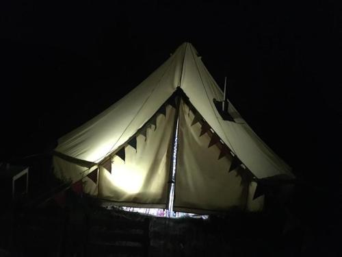 une tente blanche éclairée dans l'obscurité dans l'établissement Zeltferien Into The Wäid Zelt Unter Der Esche, à Ennetmoos