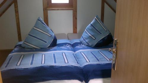 a bed with blue pillows on top of it at Ferienwohnungen Goller in Großkoschen