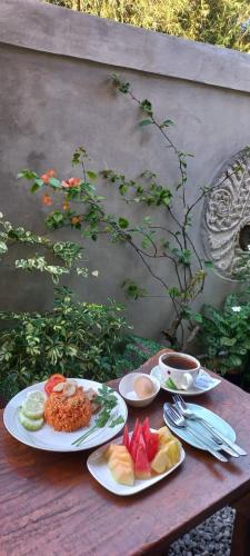 a wooden table with plates of food on it at Kubu Nadhi in Ketewel