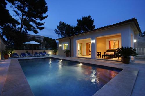 une piscine devant une maison la nuit dans l'établissement Villa Medina, à Cala Sant Vicenç