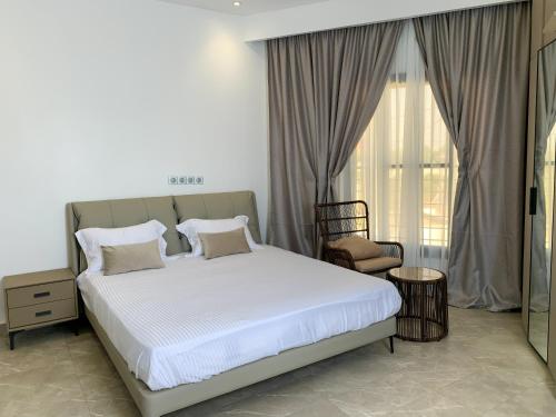 a bedroom with a bed and a chair and a window at la Villa WOOR Saly Joseph in Mbour