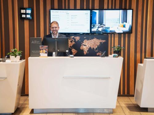a man sitting at a counter with a laptop at Novotel Lodz Centrum in Łódź