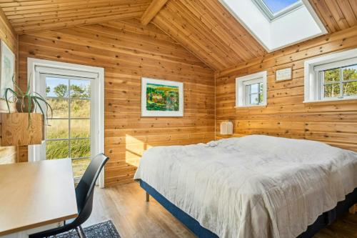 een slaapkamer met een bed, een tafel en stoelen bij Timber House On Dune Plot Near Hulsig in Hulsig