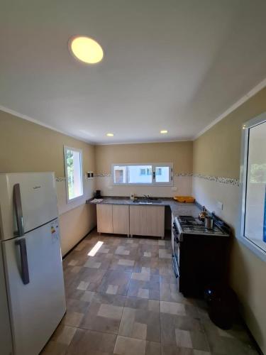 a large kitchen with a white refrigerator and a tile floor at Cabañas Valle Nabú in Lago Puelo
