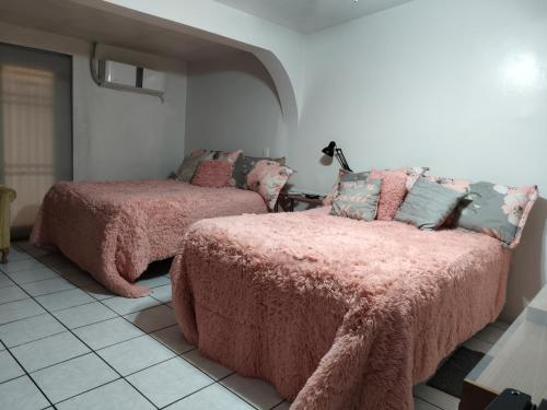 ein Schlafzimmer mit zwei Betten mit rosa Decken und Kissen in der Unterkunft la casa de la tia Lucita in Ciudad Juárez