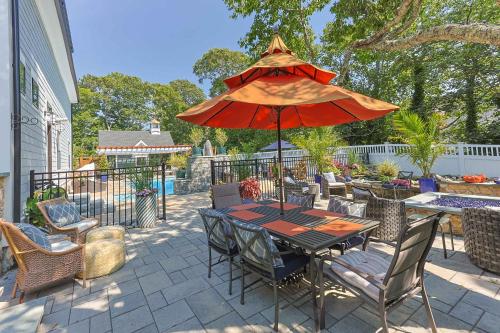 een patio met een tafel met een rode parasol bij Heated Pool Outdoor Kitchen Luxury Living in Harwich