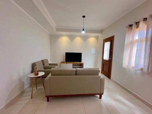 a living room with a couch and a tv at Vila dos Pinheiros 2 in Serra Negra