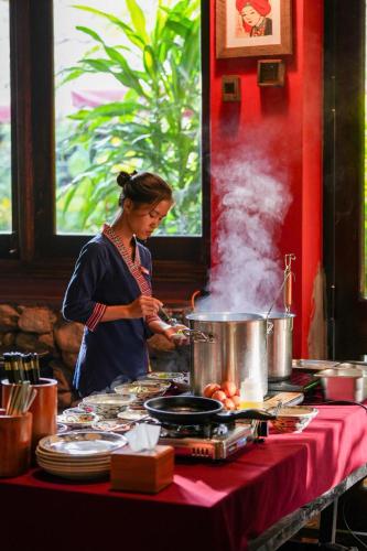 a woman standing at a table preparing food at Panhou Retreat in Ha Giang