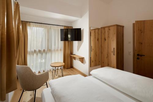 a bedroom with a bed and a chair and a window at Die Monika Aparthotel in Gaschurn