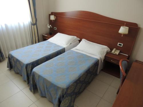 a hotel room with two beds and a wooden headboard at Hotel Rigolfo in Moncalieri