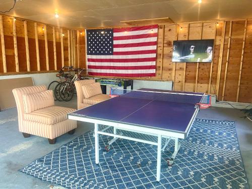 a ping pong table in a room with an american flag at Steps From Downtown Minutes From Grays Beach in Yarmouth