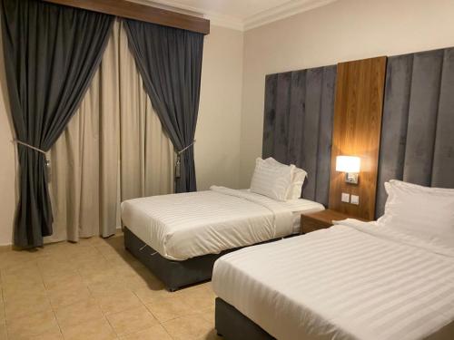 ein Hotelzimmer mit zwei Betten und einem Fenster in der Unterkunft منازل الخليج للشقق الفندقية in Dammam