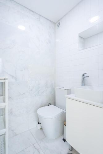 a white bathroom with a toilet and a sink at River & Beach Apartment near Lisbon in Trafaria