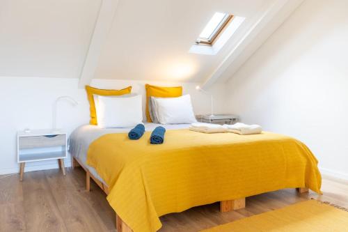 a bedroom with a yellow bed with two blue slippers on it at River & Beach Apartment near Lisbon in Trafaria