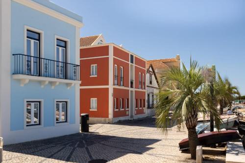 a building with a palm tree next to a street at River & Beach Apartment near Lisbon in Trafaria