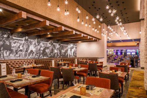 a restaurant with tables and chairs and a mural of horses at Derby City Gaming & Hotel - A Churchill Downs Property in Louisville