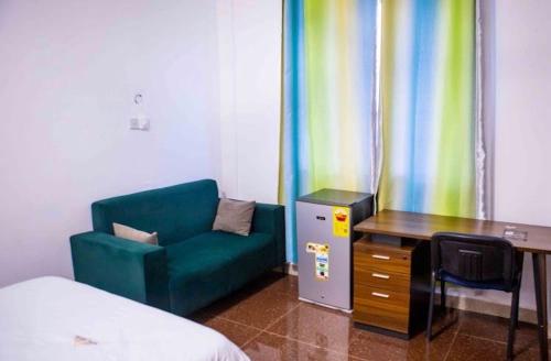 a room with a green couch and a desk and a table at Hotel Spintex and tours in Accra