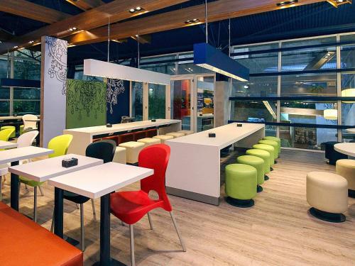 un restaurant avec des tables blanches et des chaises colorées dans l'établissement ibis budget Sao Paulo Paraiso, à São Paulo