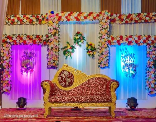 un canapé devant une scène avec des fleurs dans l'établissement Hotel Gagan Jyoti And Banquet Hall, à Rudrapur