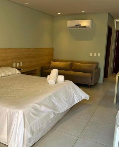 ein Schlafzimmer mit einem weißen Bett und einer Couch in der Unterkunft Villas BobZ - Ap Taiti 304 in Barrinha