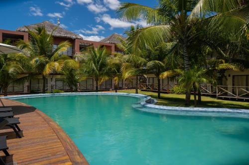 ein Swimmingpool vor einem Resort mit Palmen in der Unterkunft Villas BobZ - Ap Taiti 304 in Barrinha