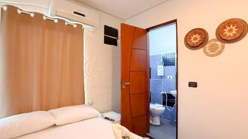 a bedroom with a bed and a bathroom with a toilet at Pousada Maken Hary - Centro in Arraial d'Ajuda