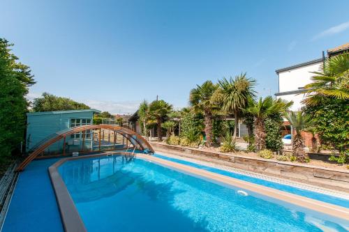 a swimming pool with a wooden bridge over it at Botany Bay Beach House - Stunning Sea Views in Kingsgate