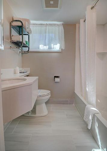 a white bathroom with a toilet and a sink at Skaket Beach Motel in Orleans
