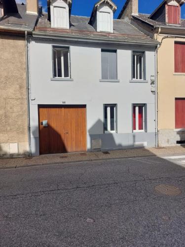 ein weißes Haus mit einer Holztür auf einer Straße in der Unterkunft La Saint-Mametoise in Saint-Mamet