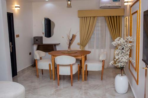 a dining room with a table and white chairs at Little Afrika in Port Harcourt