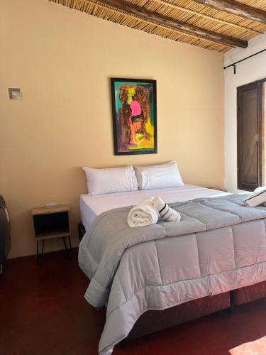 a bedroom with a large bed with a picture on the wall at Hostería Los Morteros in Purmamarca
