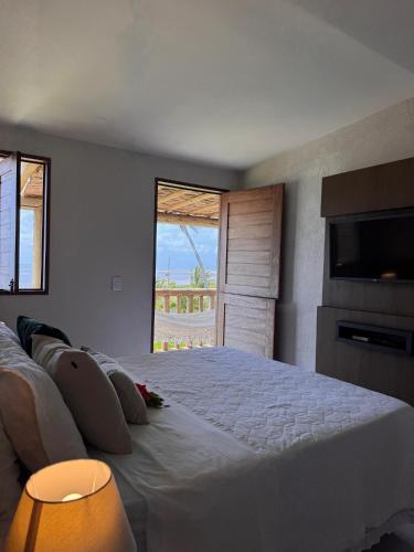 a bedroom with a large white bed and a window at Condomínio Praias de Maragogi & Casas Deluxe in Maragogi