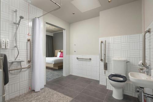 a bathroom with a toilet and a sink and a shower at Moxy Dublin Docklands in Dublin