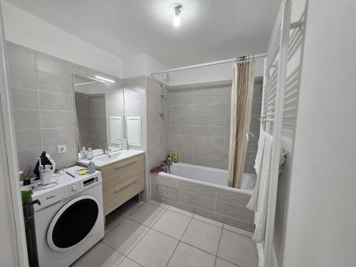a bathroom with a tub and a sink and a washing machine at Face au Métro 14, Chambre avec balcon et vue sur jardin, 5 min Orly, 7 min Paris in Chevilly-Larue
