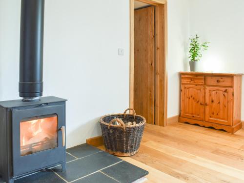 a living room with a wood stove and a basket at Slade Barn - Uk42977 in Highbray