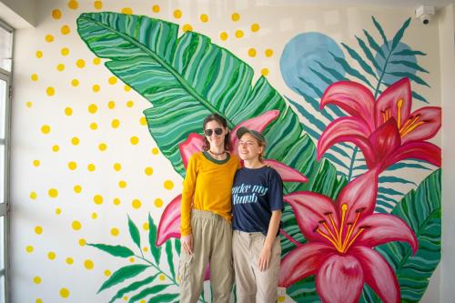 Zwei Personen stehen vor einem Blumenwandbild. in der Unterkunft HOSPEDAJE JOSUE - paracas in Paracas
