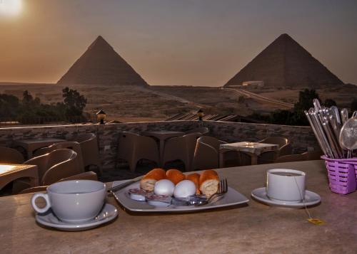 Una mesa con un plato de huevos y tazas de café. en TuT Pyramids View, en El Cairo