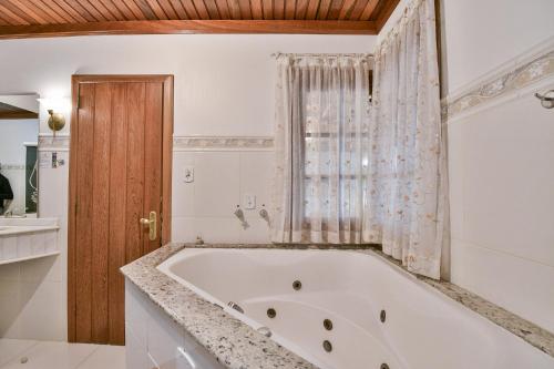 a white bath tub in a bathroom with a window at Hotel Tirol in Treze Tílias