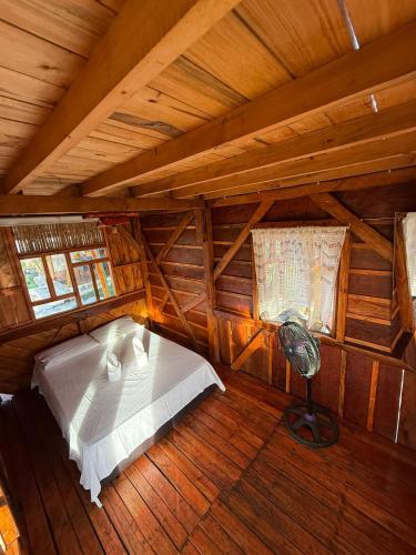 a bedroom in a log cabin with a bed and a fan at Wila Hostal in Gigante