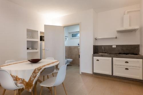 een witte keuken met een tafel en witte stoelen bij Masseria Nanni in Gallipoli